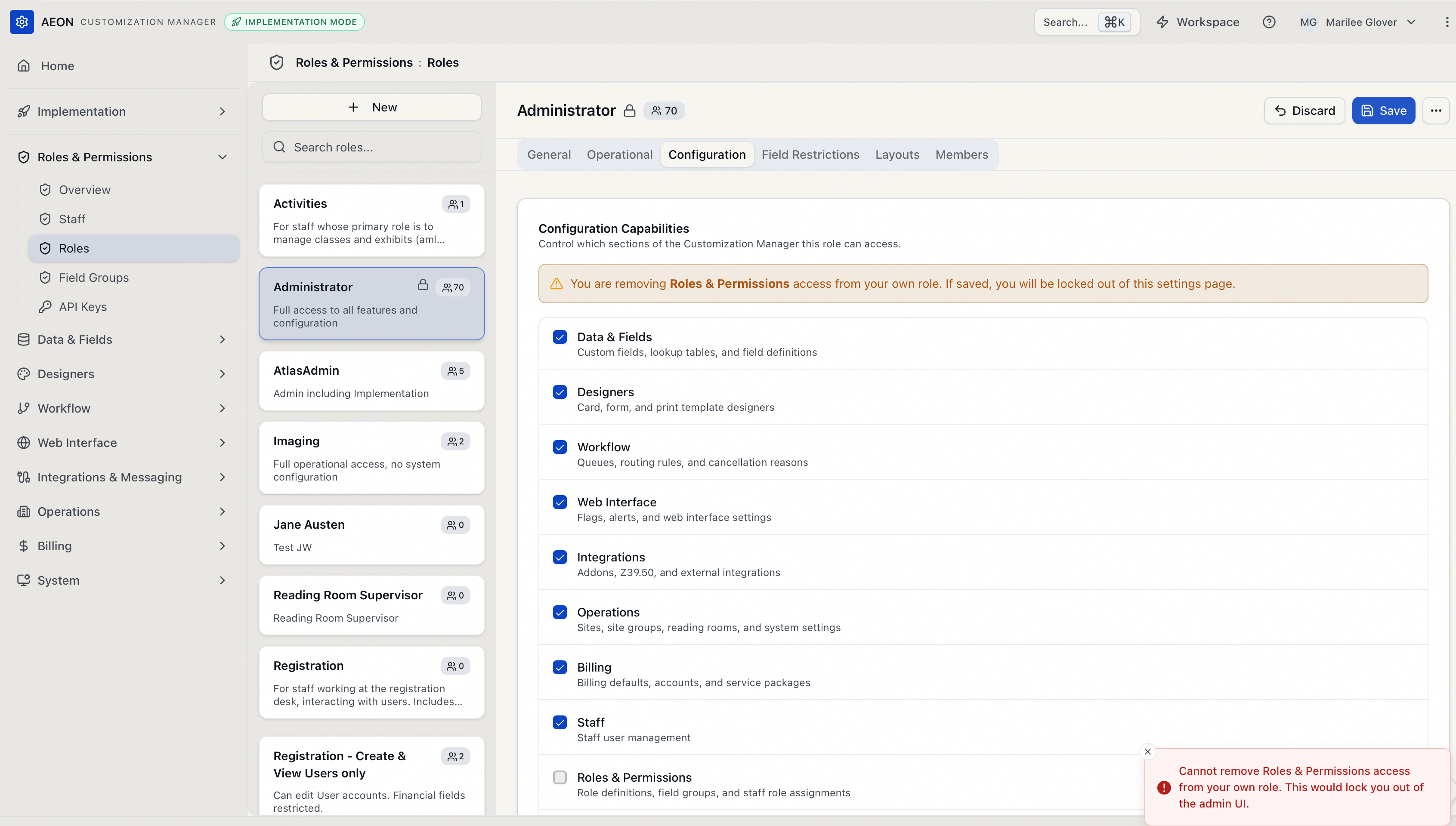 The role editor's Configuration tab in the self-lockout case: the amber inline warning above the capability list, and the red toast reading "Cannot remove Roles & Permissions access from your own role. This would lock you out of the admin UI." after clicking Save