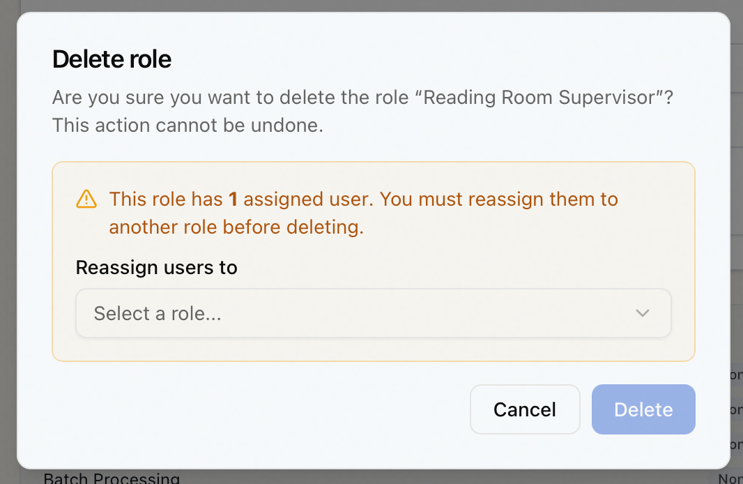 The Delete role dialog for a role with assigned users — the amber reassign-before-deleting warning and the Reassign users to dropdown